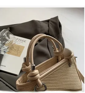 Detail of beige woven bucket bag with smooth leather handle and silver metal rings