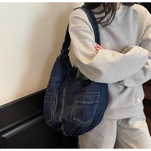 Detailed view of dark blue denim hobo bag with yellow contrast stitching and pockets