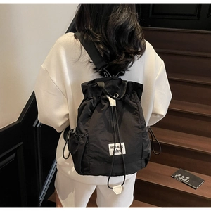 Detail view of lightweight black nylon drawstring backpack with square printed patch on model
