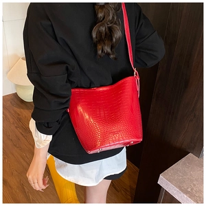 Detail of red crocodile texture bucket bag showing glossy finish and metal feet on base