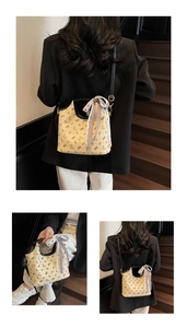 Detailed macro view of beige bucket bag with bear print and decorative checkered silk bow