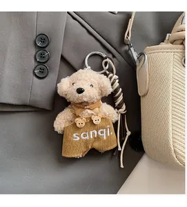 Close-up of fluffy brown bear charm wearing yellow corduroy overalls with embroidery