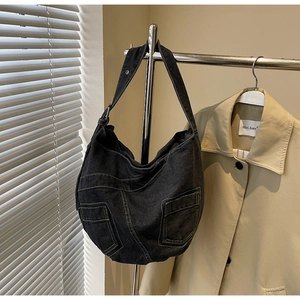 Detail of black denim hobo bag showing yellow contrast stitching and front pockets