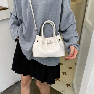 Nahaufnahme einer weißen gefalteten Beuteltasche mit Zierschnalle am Outfit des Models