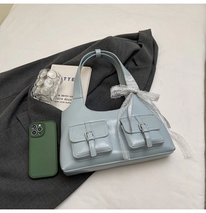 Dettaglio della borsa tote azzurra in ecopelle con fibbie metalliche e fiocco in pizzo