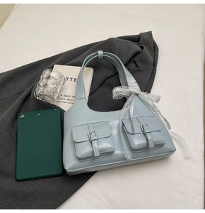Dettaglio della borsa azzurra con fiocco e due tasche anteriori con fibbie