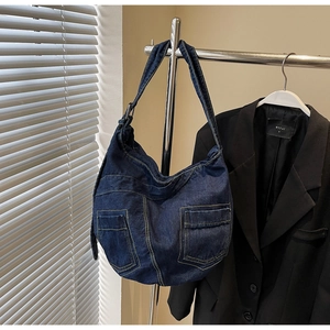 Detail of dark blue denim shoulder bag showing vintage wash texture and utility pockets