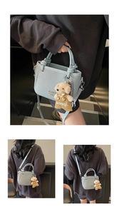 Detail view of light blue woven texture bucket bag with bear pendant and metal logo