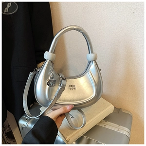 Detail of silver metallic crescent bag featuring white resin rings and metal pendants