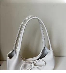 Detail view of the soft PU leather texture and decorative bow on this beige tote bag