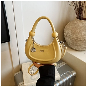 Close-up of bright yellow crescent bag with a decorative knot handle and G metal charm