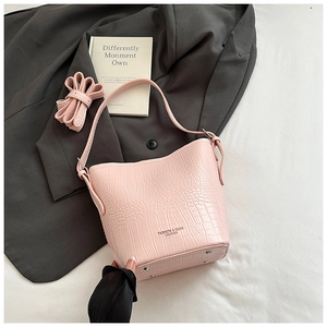 Detailed view of pink crocodile pattern bucket bag with metal protective feet and strap
