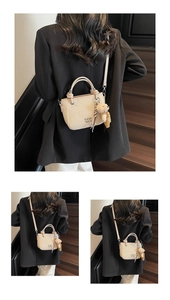 Detail view of beige textured bucket bag with teddy bear charm and adjustable shoulder strap