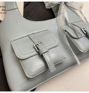 Dettaglio borsa tote azzurra con tasche metalliche e fiocco decorativo in pizzo