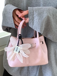 Rosafarbene Handtasche mit Krokodilmuster, dekorativem Blumenanhänger und Schultergurt