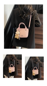 Close-up of pink bucket bag with ripple texture, metal logo and a small bear charm