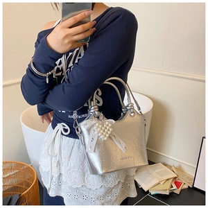 Detailed close-up of silver bucket bag featuring metallic pleated texture and pearl heart charm