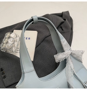 Vista dettagliata della borsa tote azzurra con fiocco in pizzo e tracolla in pelle PU