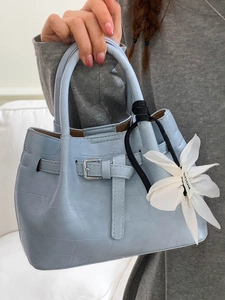 Hellblaue Eimertasche mit Krokodilmuster, großer weißer Blume und Gürteldetail