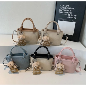 Detail shot of five mini bucket bags in different colors with cute bear charms on steps