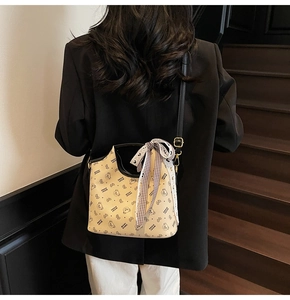 Detail of beige bucket bag featuring cartoon bear print and decorative checkered bow accent