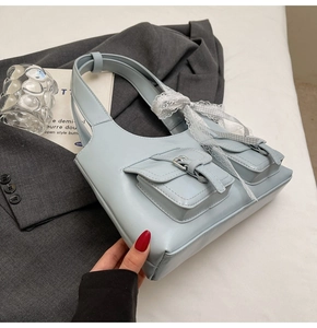 Dettaglio borsa tote azzurra in ecopelle con fiocco in pizzo e tasche con fibbia
