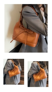 Detail view of brown PU leather shoulder bag with decorative bow and reinforced bottom base