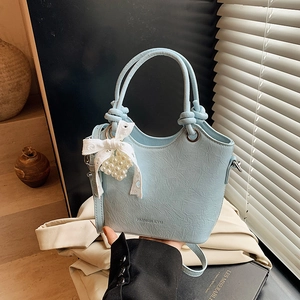 Detailed close-up of sky blue bucket bag with lace bow and pearl heart pendant charm