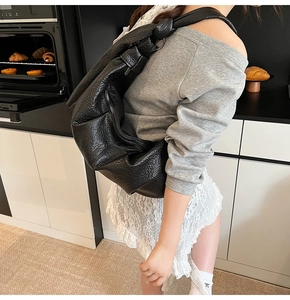 Detail of black pleated shoulder bag with litchi texture and knotted strap detail