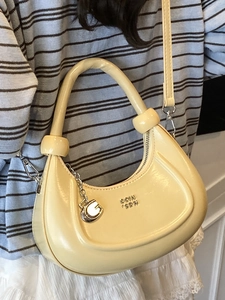 Chic pale yellow crescent bag in glossy faux leather with G-pendant and shoulder strap