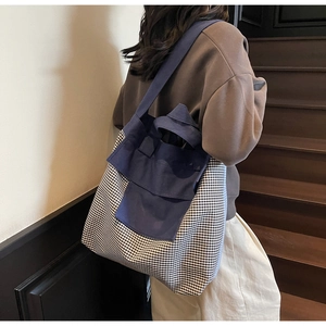 Detail of navy canvas and black-white checkered tote bag worn on a shoulder