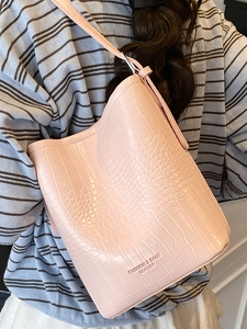 Light pink crocodile pattern bucket bag with adjustable strap and minimalist design