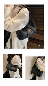 Detail of a black Hobo shoulder bag with a bow accent worn on a wooden staircase