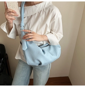 Close-up of sky blue croissant bag showing litchi texture leather and knotted strap detail