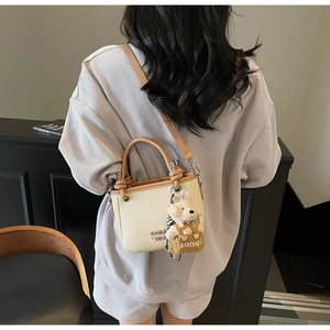 Detail view of woven bucket bag with leather strap and cute plush bear charm accessory