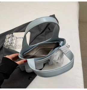 Dettaglio dell'interno della borsa celeste con tasca a zip e fiocco in pizzo decorativo
