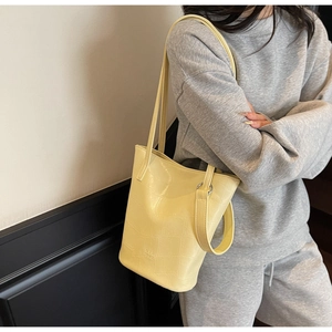 Detail of light yellow crocodile pattern tote bag showing glossy texture and shoulder strap