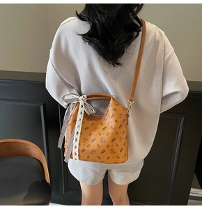 Detail of caramel tote bag featuring cartoon bear print and black-and-white ribbon bow