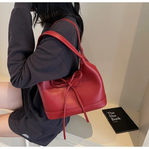 Close-up of a red PU leather shoulder bag with a stylish bow drawstring design