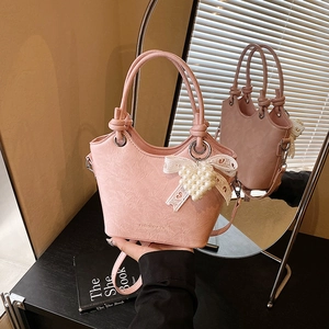 Detail of pink bucket bag with pleated texture, knot handle and heart pearl charm