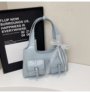 Dettaglio borsa tote azzurra in ecopelle con fiocco in pizzo e fibbie metalliche