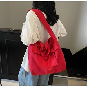 Detail of red canvas tote bag with ruffle design worn by a model in casual white shirt