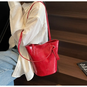 Detail of red crocodile pattern bucket bag showing textured leather and brand embossing