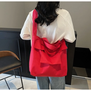 Rear view of a large red canvas tote bag with wide straps worn with casual white t-shirt