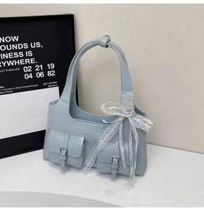 Dettaglio della borsa tote azzurra con tasche laterali e accessorio a fiocco elegante