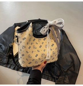 Detail view of beige bucket bag with bear print and large checkered lace bow accessory