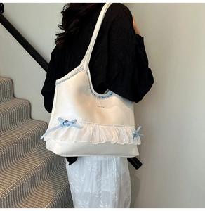 Close-up of cream PU leather tote with organza ruffles and light blue ribbon bows