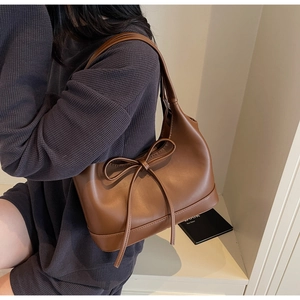 Brown PU leather hobo bag with ribbon bow detail shown in a stylish lifestyle scene