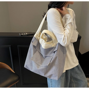 Blue and white striped canvas tote bag shown on shoulder in a stylish home setting