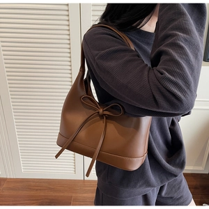 Brown PU leather shoulder bag with bow detail shown on model in natural light setting